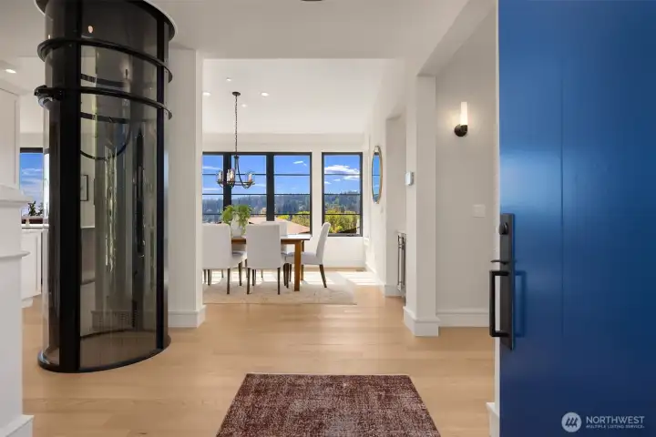 Front entrance via custom door with panoramic territorial and water views. Modern elevator provides service between main floor and upper level primary suite.