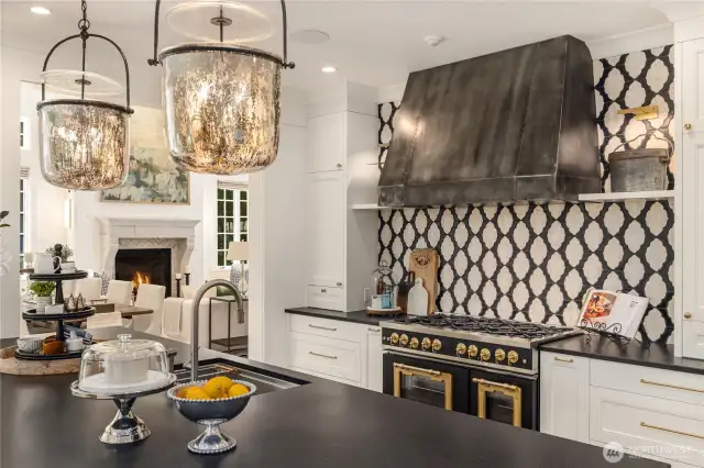 Backsplash features Tabarka tiles with hand placed fossil impressions.  Iron hood by Rory's Custom Fabrications. Lorford Smoke Bell Lanterns in aged iron with mercury glass by Visual Comfort