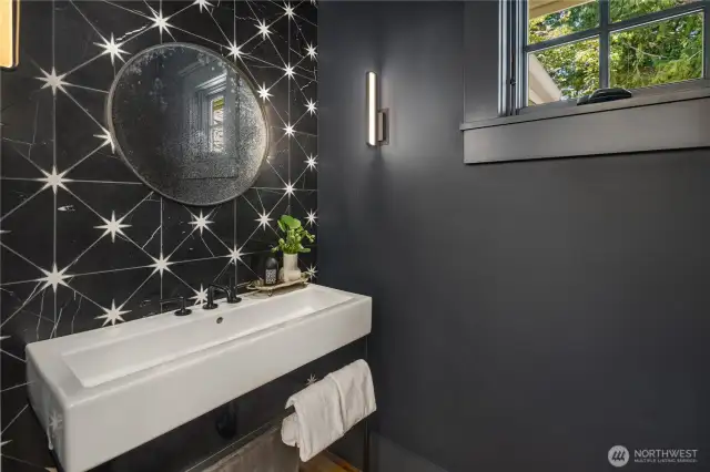 Sparkling powder room features a Cheviot Console Lavatory sink in gloss white with matte black finish and a   Clooney antiqued round wall mirror