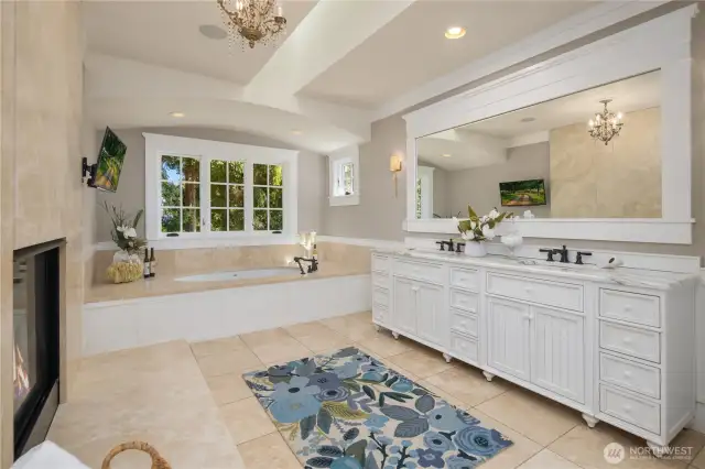 Luxurious spa bathroom with dual sink vanity, soaking tub, radiant heated hearth, and radiant floor heat