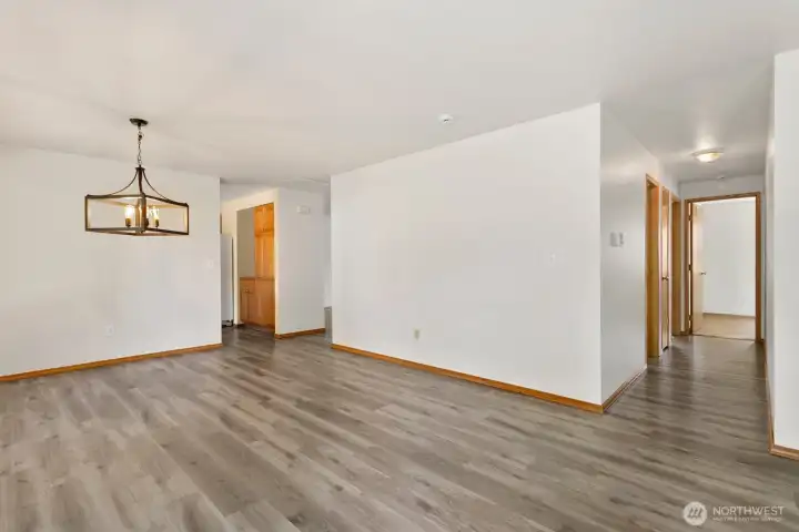 View from family room down bedroom hallway on right, kitchen entry to right of dining room light fixture