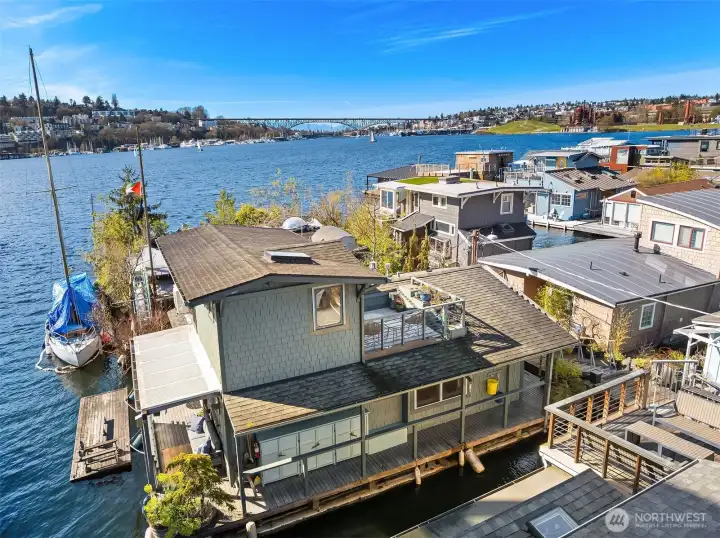 An aerial view captures the home's enviable position on Lake Union, surrounded by water, with the Aurora Bridge, Queen Anne, and the Eastlake floating home community all in view.