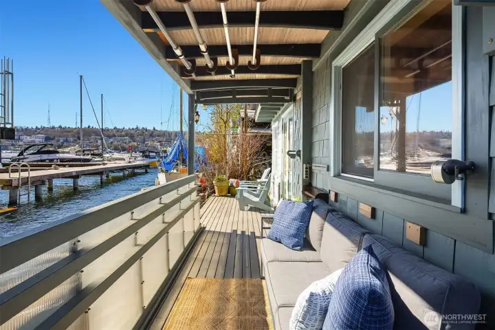 A long covered deck runs alongside the home, offering a sheltered outdoor living space with water views in any weather.