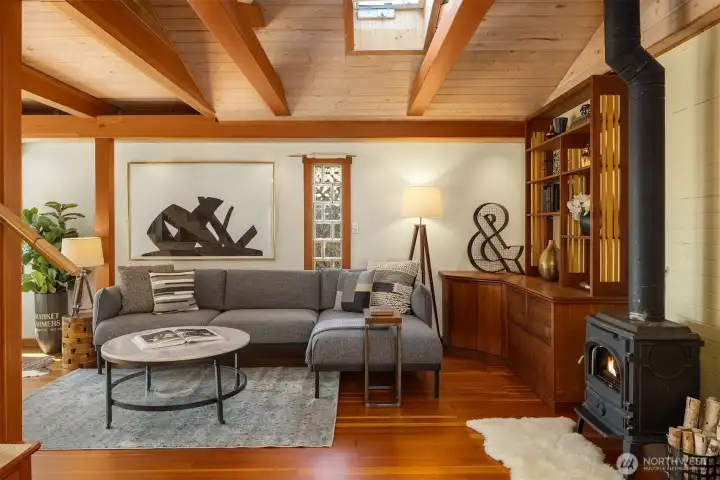 The living room's full sweep of vaulted beams, skylights, wood stove, built-ins, and gleaming hardwood floors.