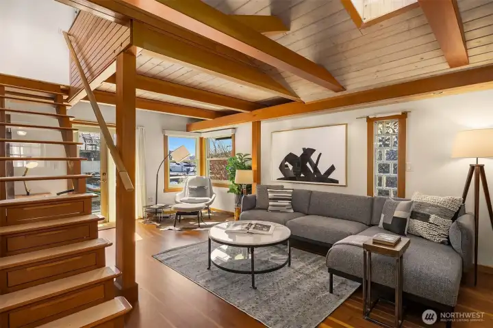 Dramatic vaulted ceilings with exposed Douglas fir beams, a skylight overhead, and a beautiful wood staircase make the living room the architectural heart of the home.