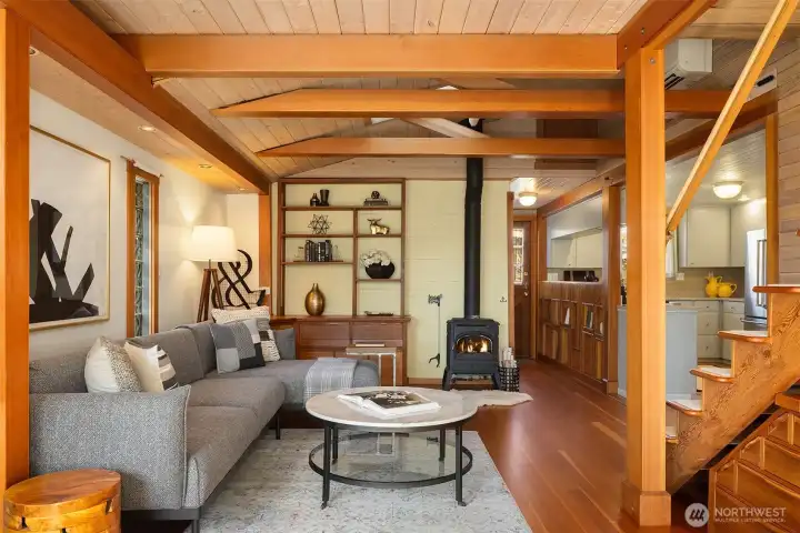 The living room's built-in credenza and bookshelf wall, paired with the wood stove and beamed ceiling, give the space the soul of a well-loved cabin — right in the city.