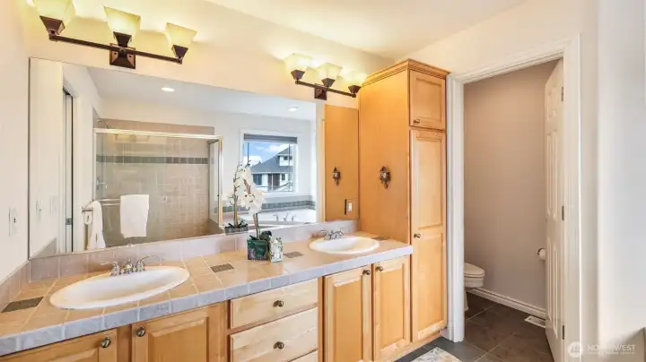 This space features double sinks, abundant cabinetry, and a private water closet