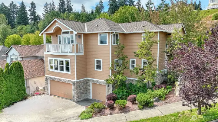 This refined home features stone and siding exteriors, complemented by mature trees and beautifully maintained landscaping.