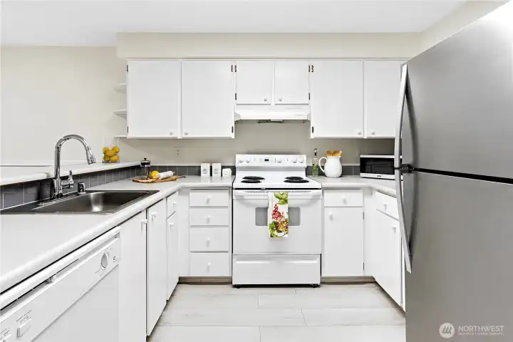 Delightful kitchen with newer 2021 stainless refrigerator, newer sparkling faucet, newer light fixtures and tiled backsplash ready for all your culinary creations. Delightful kitchen with newer 2021 stainless refrigerator, newer sparkling faucet, newer light fixtures and tiled backsplash ready for all your culinary creations.