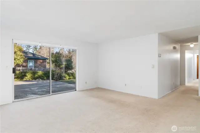 Large living room with sliding doors that lead out to the fenced yard.