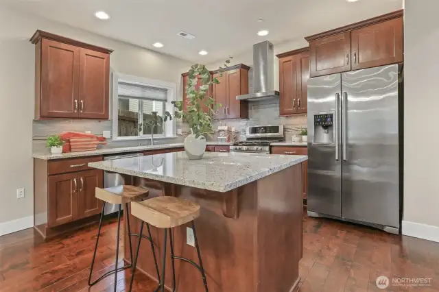 The kitchen has an island with slab granite, soft close cabinets, stainless steel appliances and a pantry.