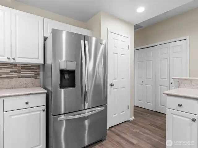 Kitchen features stainless steel appliances and pantry cabinet. Laundry cabinet beyond with washer & dryer hook-ups.