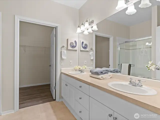 Full bathroom off of primary bedroom with double sink vanity and walk-in closet