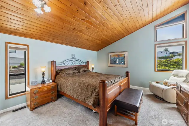 Spacious primary with a walk-in closet and vaulted wood ceilings.