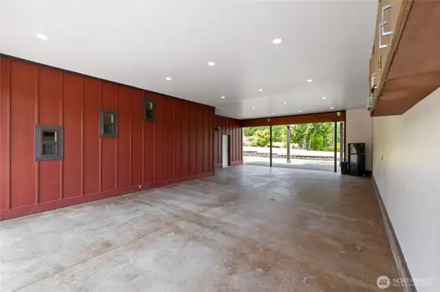 The oversized carport showcases striking exposed Glulam beams, is equipped with 50-amp service, and is illuminated by a multitude of ceiling lights—perfect for projects, storage, or entertaining. R48 Insulation in carport ceiling.