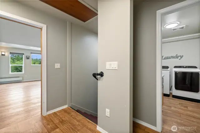 The home offers two separate living spaces, divided by a spacious laundry room equipped with a utility sink. A connecting hallway features a walk-in storage closet, additional wall-mounted storage cupboards, and convenient pull-down attic access with a built-in ladder.