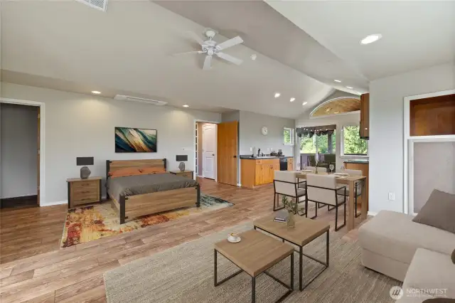 To the right of the couch, a wall cabinet and shelf provide additional storage. The spacious layout of the room offers endless possibilities for customization. A large storage closet is located to the left of the bed, while the covered balcony—accessible through sliding glass doors—extends the living space and invites the outdoors in. Abundant windows fill the room with natural light and showcase expansive views of the beautiful property.