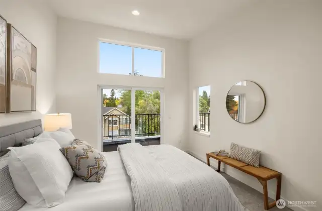 The primary bedroom is a sanctuary of natural light, featuring vaulted ceilings, large windows, and private balcony access. Wake up to serene views and unwind in your peaceful haven. Photos of home with similar layout, finishes & fixtures.