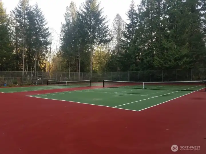 Double tennis courts outside clubhouse with community gardens behind.