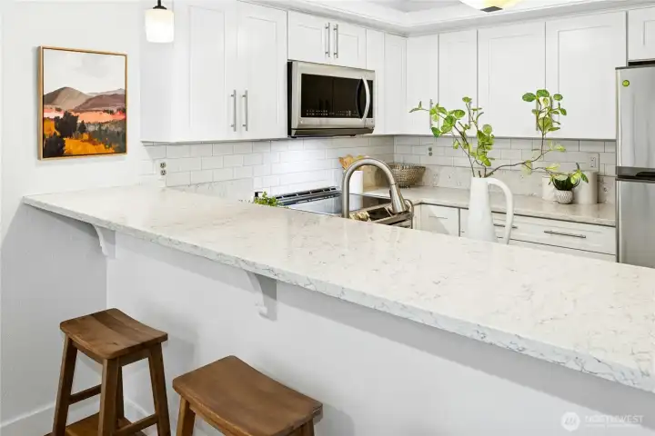 The efficient U-shaped kitchen has a gas range, large pantry, and an eating bar.