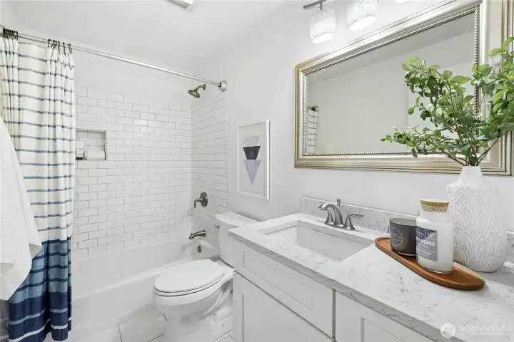 The upstairs full bath has been updated with white cabinets, quartz countertops and subway tile.
