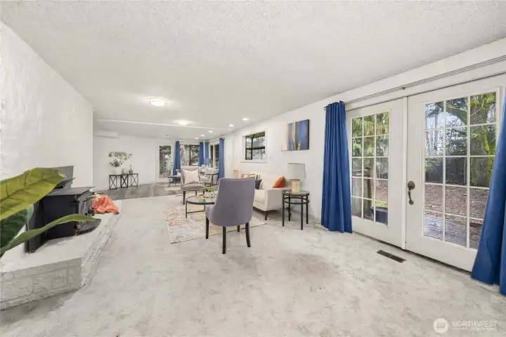 Living room has a wood fireplace insert and french doors leading to the backyard deck.