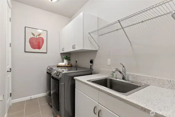 Spacious laundry room with new washer/dryer combo. Includes a convenient deep sink hanging space and enough counter space to fold.