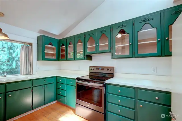 Freshly painted cabinets, glass cabinet fronts,  vaulted ceiling with skylight make for a bright welcoming kitchen.