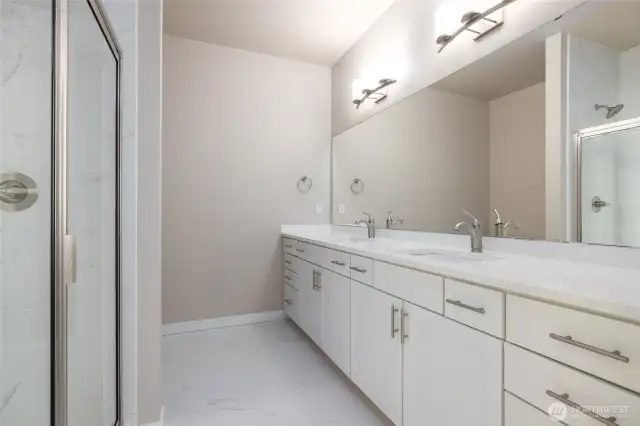 The primary bath has two sinks and an upgraded tile shower w/glass door.