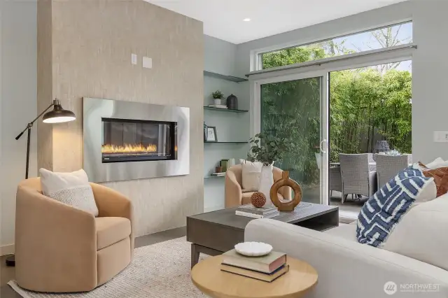 The grey ceramic flooring grounds the room, while the commanding fireplace, wrapped in warm stone tile, creates a striking juxtaposition.