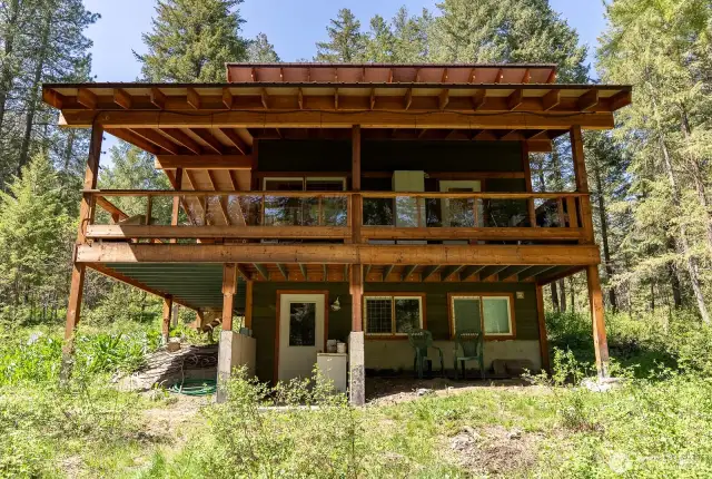 The East side of the cabin showing the poured concrete foundation, large posts and beams, and thick rafters.
