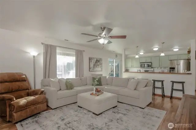 The living room is bright and inviting, with abundant natural light streaming in and a ceiling fan overhead to keep the space comfortable year-round.