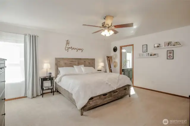 The primary suite is bright and spacious, with natural light streaming in through corner windows. It features an oversized walk-in closet, a private full bathroom, and a ceiling fan for year-round comfort—creating the perfect personal retreat.