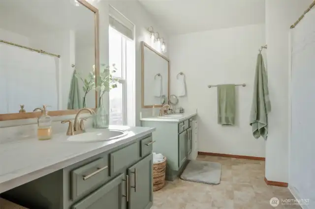 Conveniently located off the primary bedroom, this en suite bathroom includes dual vanities, a shower/tub combo, and bright, even lighting. Modern finishes add a sleek, updated feel to this comfortable and functional space.
