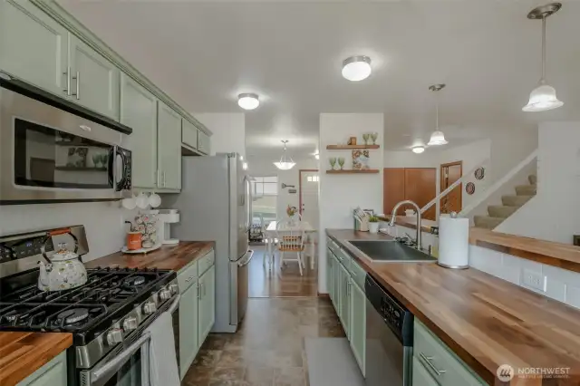 This beautifully designed kitchen features custom butcher block countertops, under-cabinet lighting, stainless steel appliances, a spacious sink, and breakfast bar seating—perfect for entertaining. Just off the kitchen, the dining area offers a seamless flow for easy meals and gatherings, all within an inviting open-concept layout.