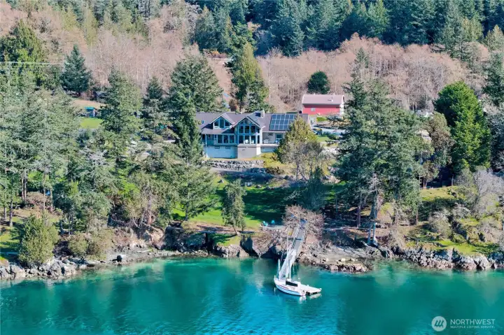 Stunning bird’s-eye view of the property’s waterfront setting, private deep-water dock, and forested surroundings