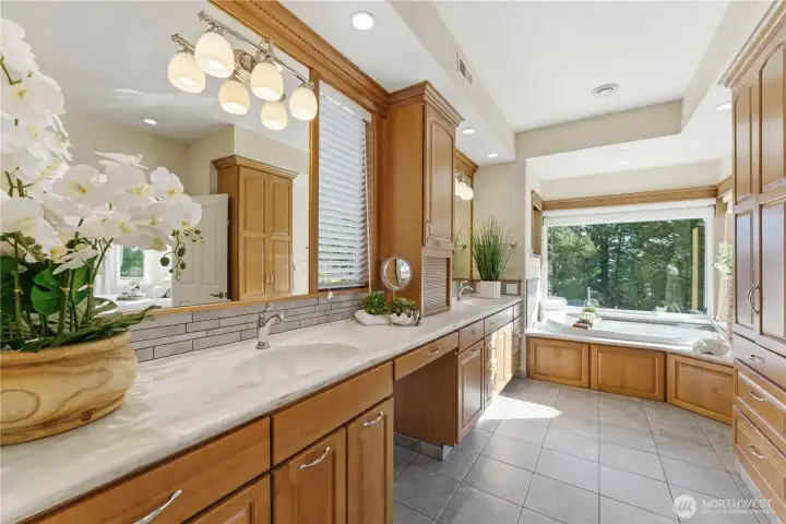 A spacious, light-filled primary bath with double vanities, a deep soaking tub, separate walk-in shower, private toilet and tranquil views - all set within a home warmed by heated floors throughout