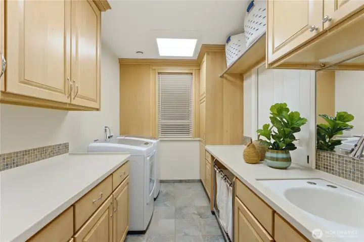 The first laundry room is bright and efficient, featuring generous storage, a sink, and thoughtful organization