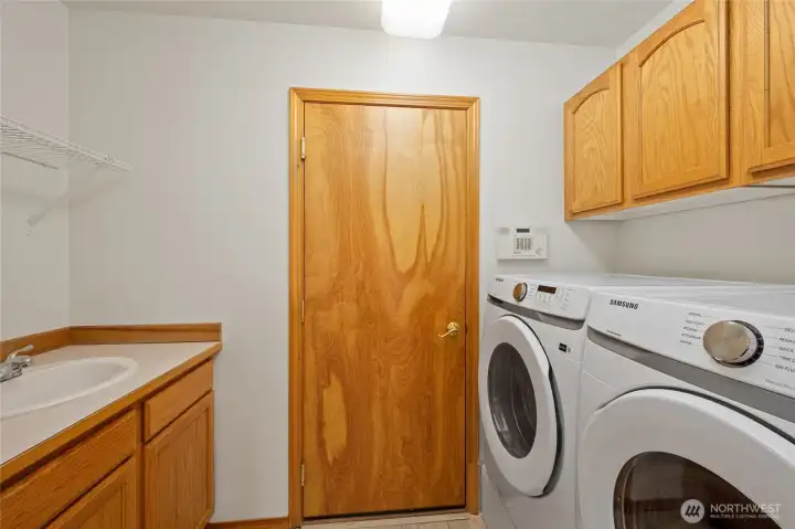 Convenient laundry room with utility sink, storage, and newer washer and dryer with garage access.