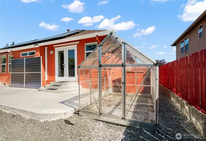 A charming greenhouse extends the growing season for gardening enthusiasts.