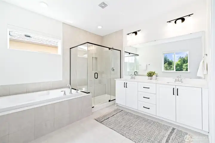 Luxurious primary bath with glass enclosed shower with tile surround