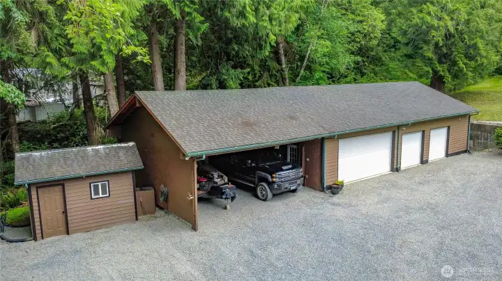 Detached shop with 4 enclosed bays + 2 bay covered parking. Well house to the left.