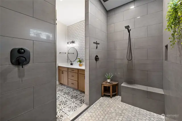 Enormous walk-in shower with bench seating, multiple water heads and window for natural light.