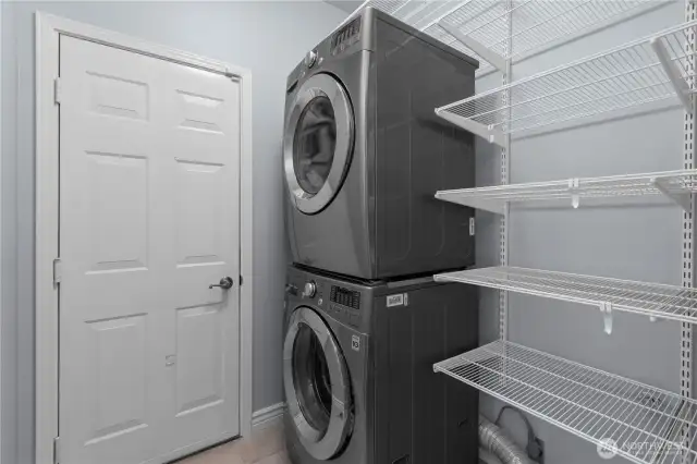 Laundry room features Stackable washer and dryer plus shelving for storage.