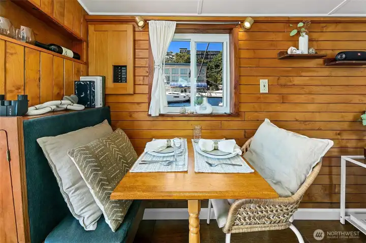 In the mess, rich wood paneling and built-in seating create a warm, intimate spot for dining or working, framed by a double-pane window that opens to fresh lake breezes.