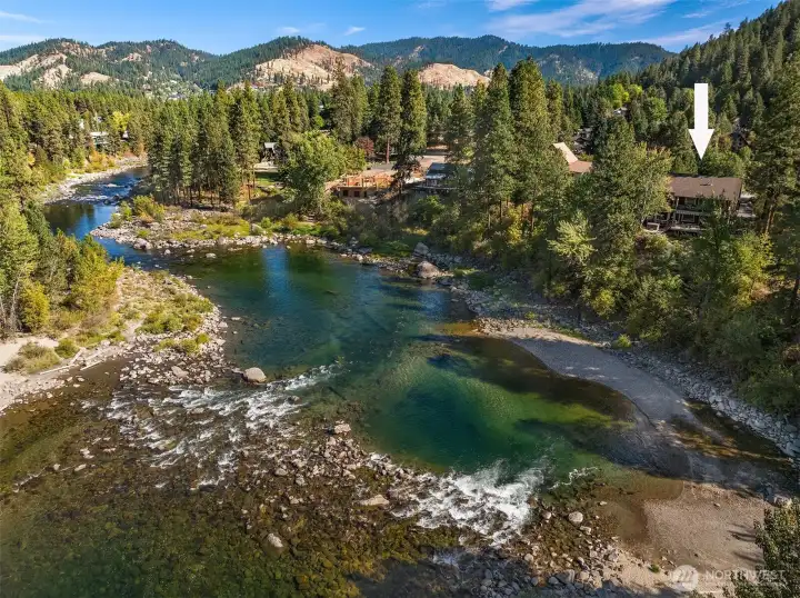 Stunning aerial of the Wenatchee River showcasing clear waters, natural shoreline, and a picturesque mountain backdrop in this highly sought-after riverfront setting.