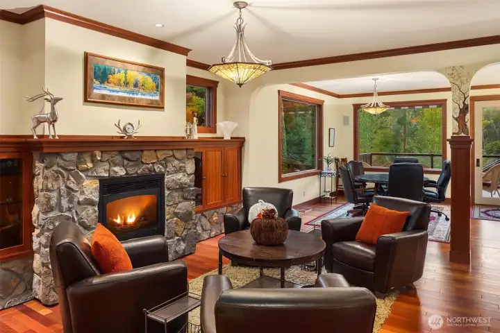 First sitting area off the entry features a warm stone fireplace, rich wood finishes, and large windows—creating an inviting space for conversation and relaxation.