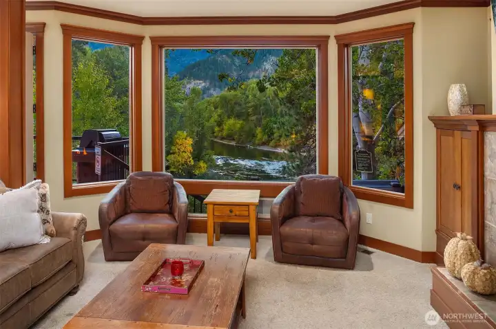 Wall of windows perfectly frames the Wenatchee River, creating a stunning focal point in this cozy sitting area with front-row views of the natural landscape.