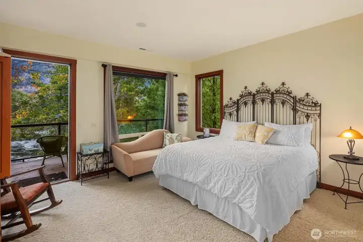 Primary suite retreat with private deck access and tranquil river views, offering a peaceful setting to relax and unwind.