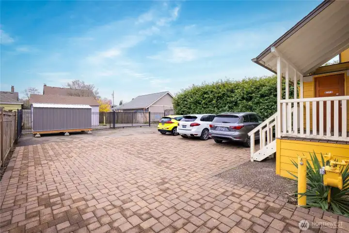 The driveway and rear parking area are fully finished with stone pavers. Additional upgrades include a storage shed and gated fencing with a rolling gate, providing convenient and secure access from the alley.